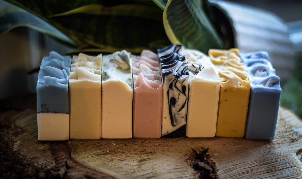 Row of colorful soap bars on a wooden surface with a natural background