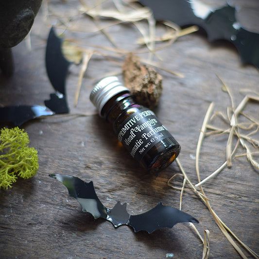 Small bottle of perfume labeled 'Vampire' on a wooden surface with decorative elements.