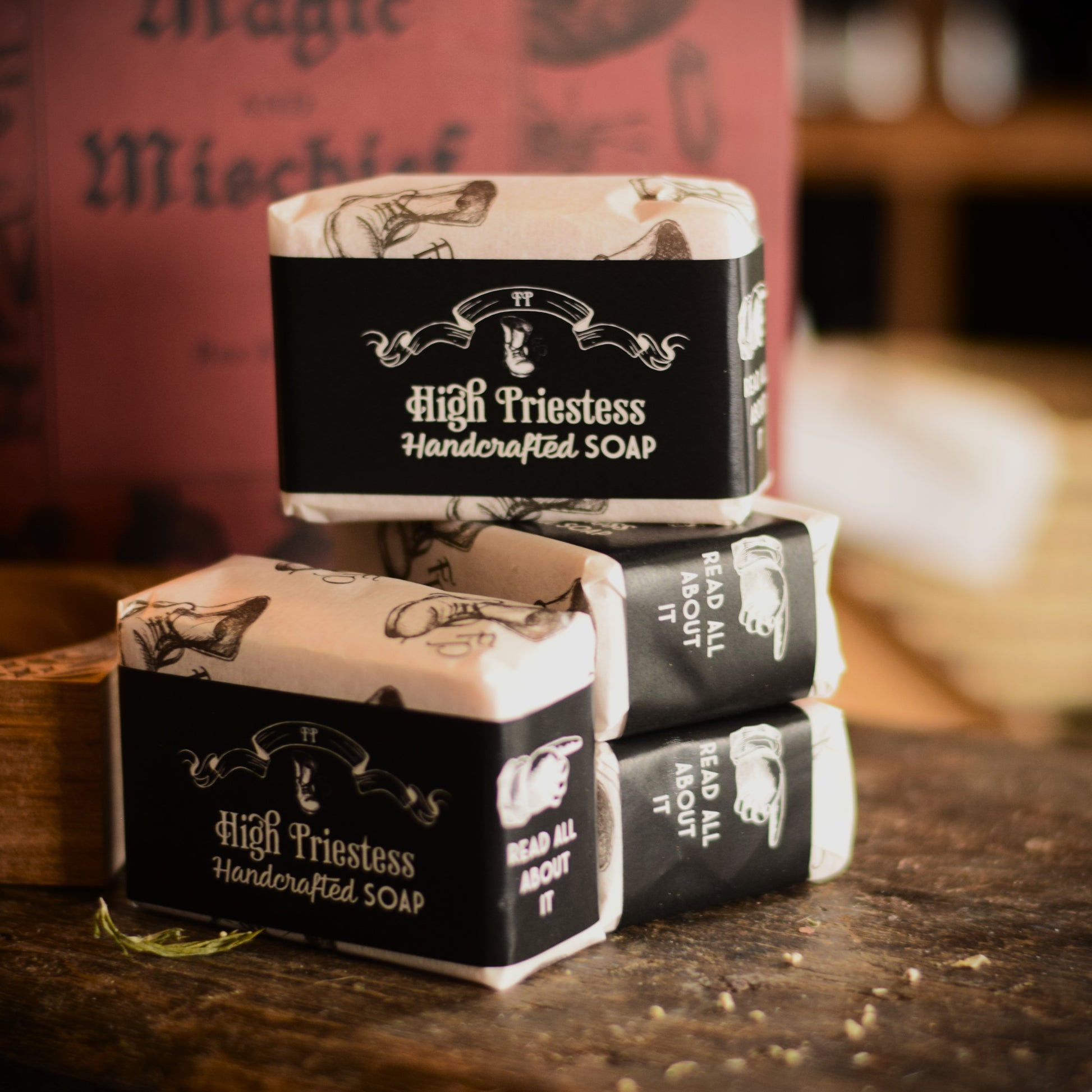 Stack of High Priestess handcrafted soap bars on a wooden surface with a blurred background.