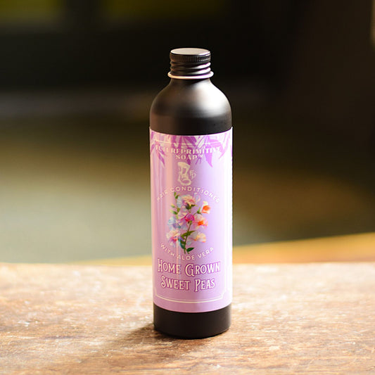 Bottle of 'Home Grown Sweet Peas' soap on a wooden surface with a blurred background