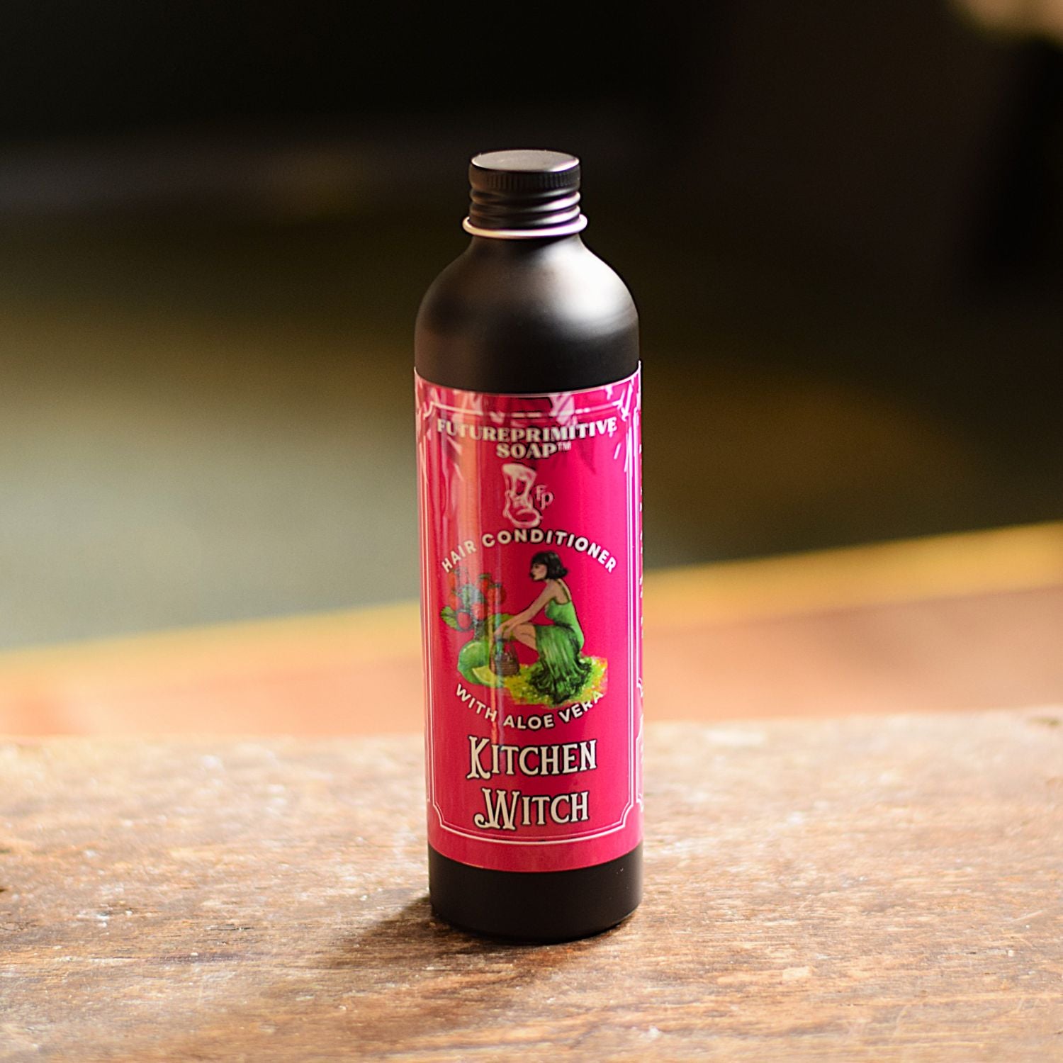 Bottle of 'Kitchen Witch' hair conditioner on a wooden surface with a dark background