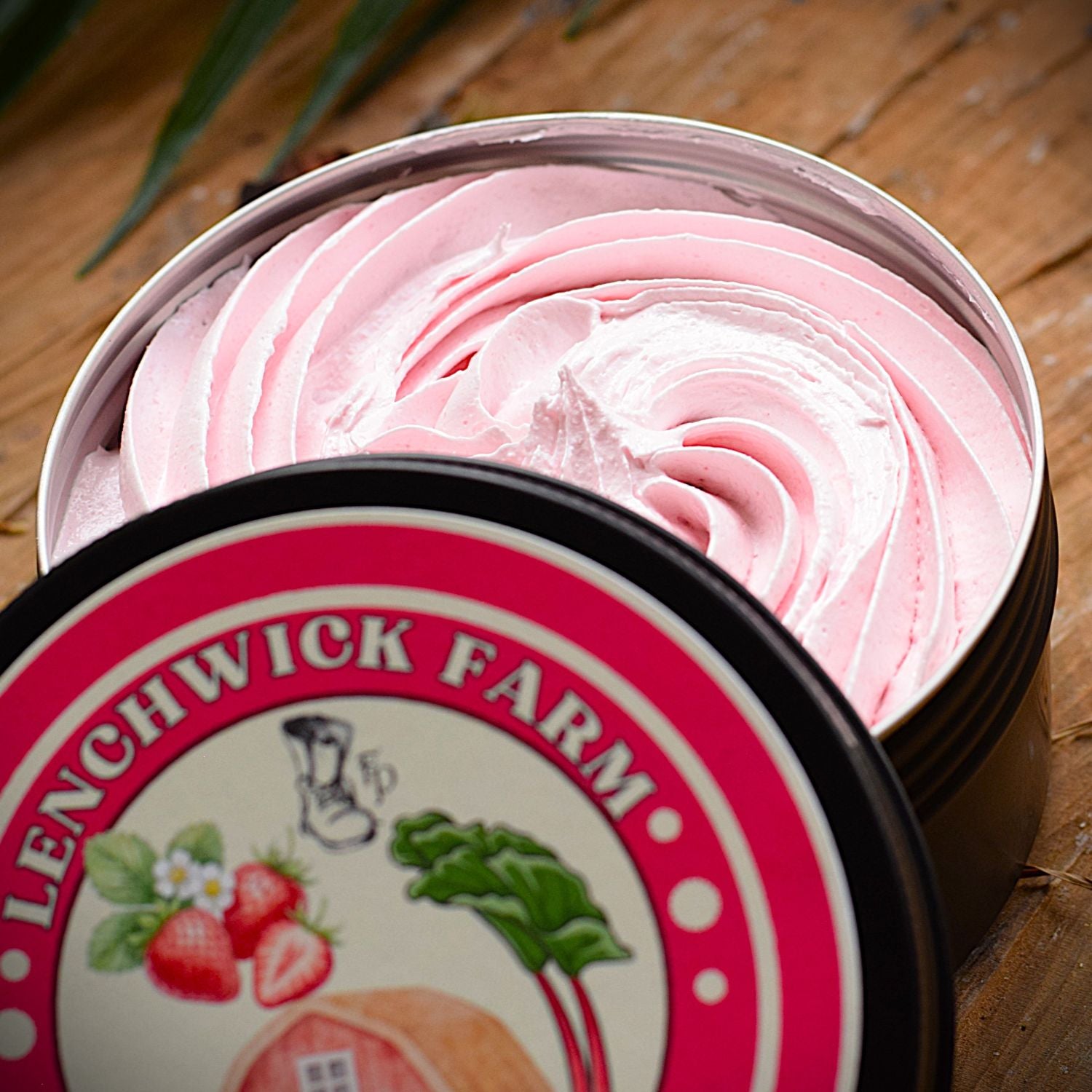 Open container of pink cream with 'Lenchwick Farm' branding on a wooden surface.