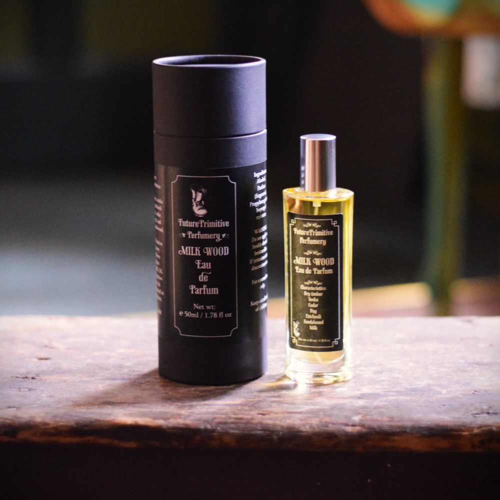 Milk Wood eau de parfum bottle and box sitting on a wooden oak table