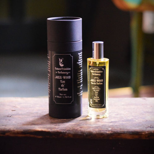 Milk Wood eau de parfum bottle and box sitting on a wooden oak table