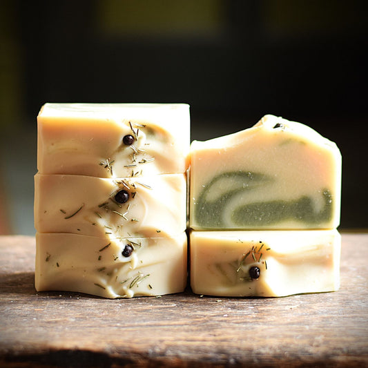 Four rectangular bars of handmade soap arranged on a rustic wooden surface. 