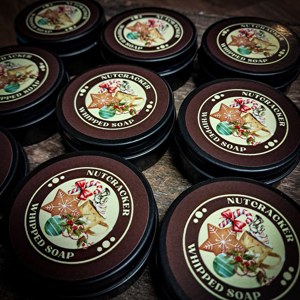 Tins of Nutcracker mini whipped soaps on a wooden surface