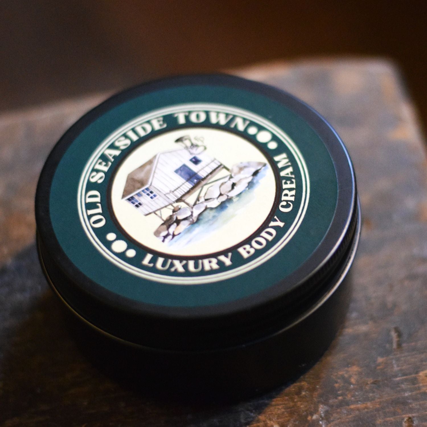 Luxury body cream container with 'Old Seaside Town' branding on a wooden surface