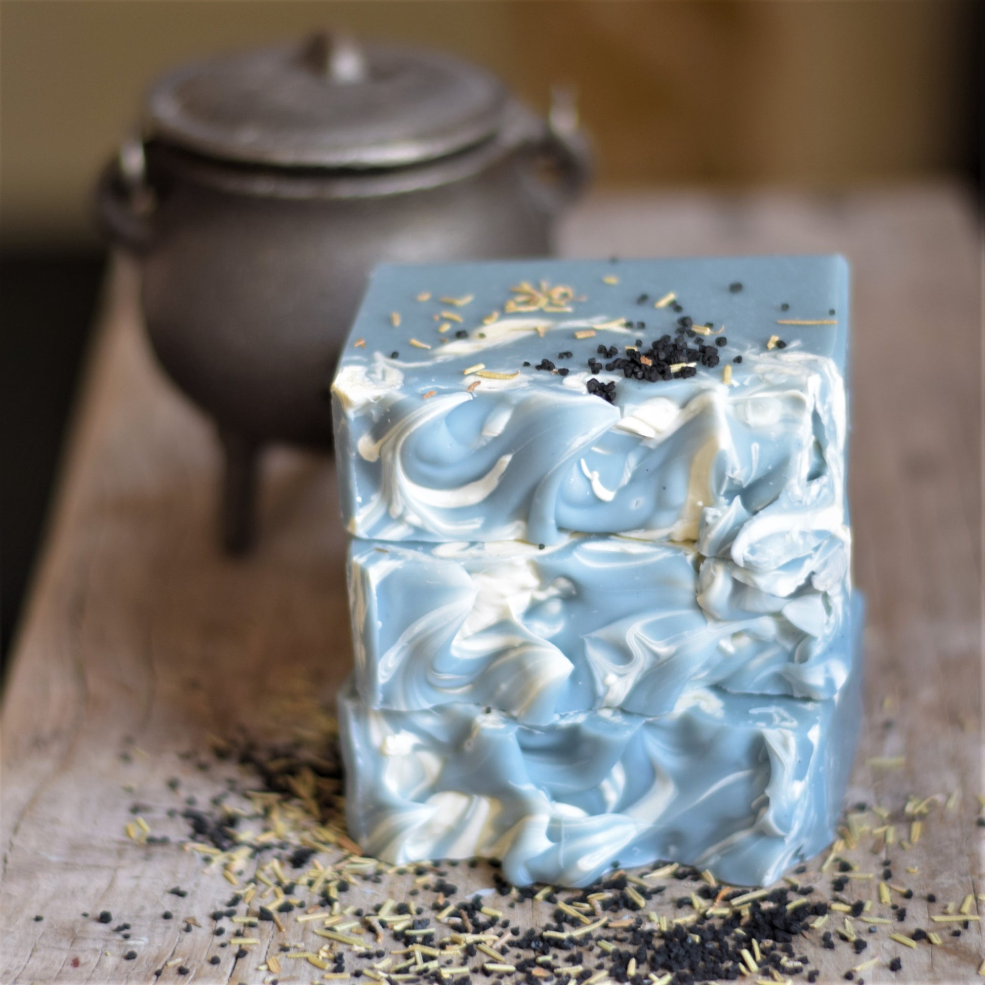 Decorative soap bar with blue and white swirls on a textured surface with a blurred teapot in the background.