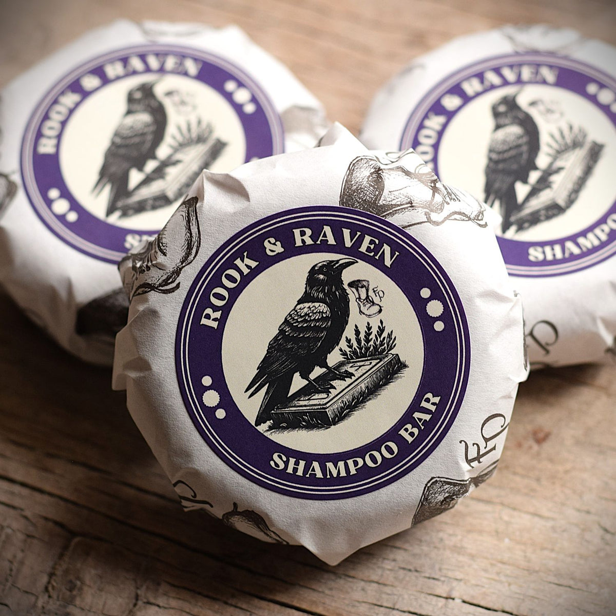 A round shampoo bar with the branding FuturePrimitive Rook and Raven sat on a wooden rustic table