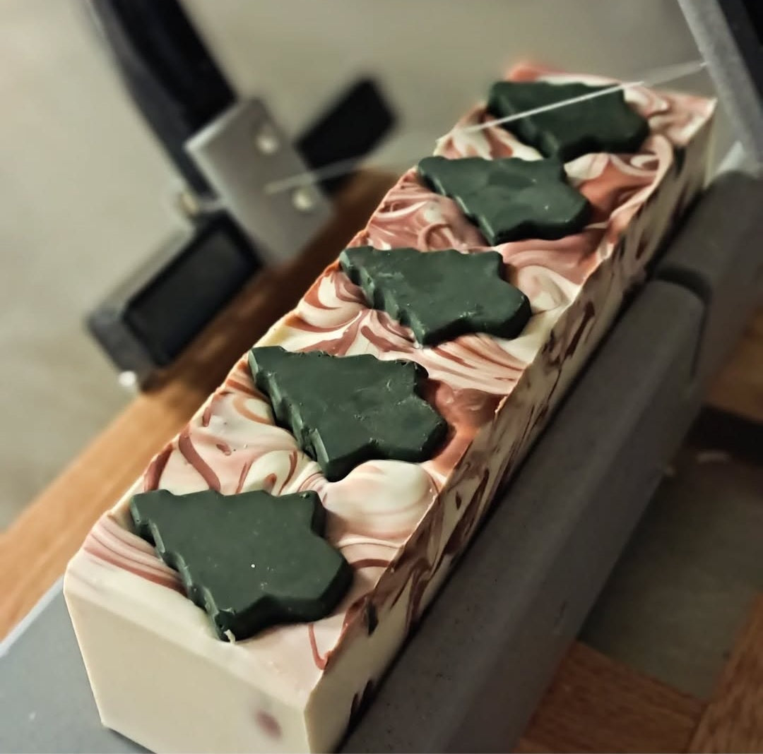 Bar of soap with green leaf-shaped bars on a pink and white striped background
