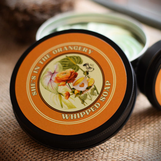Whipped soap container with decorative lid featuring floral design and text.