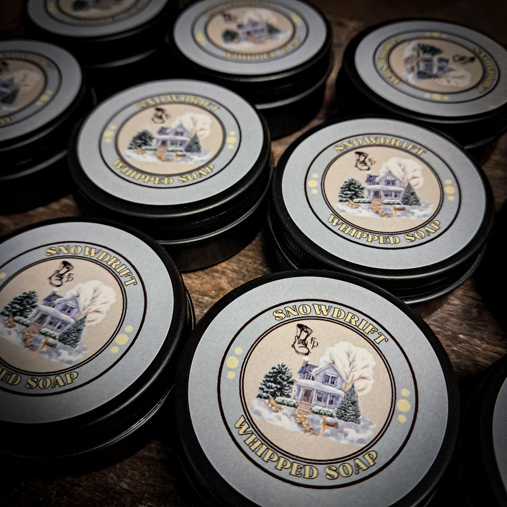 Mini tins of Snowdrift Whipped Soap on a wooden surface