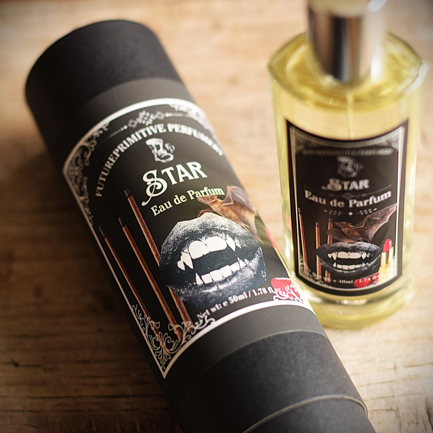 A bottle of The Lost Boys-themed Eau de Parfum and its black cardboard packaging tube, both featuring a graphic of a vampire's fangs, displayed on a rustic wooden surface.