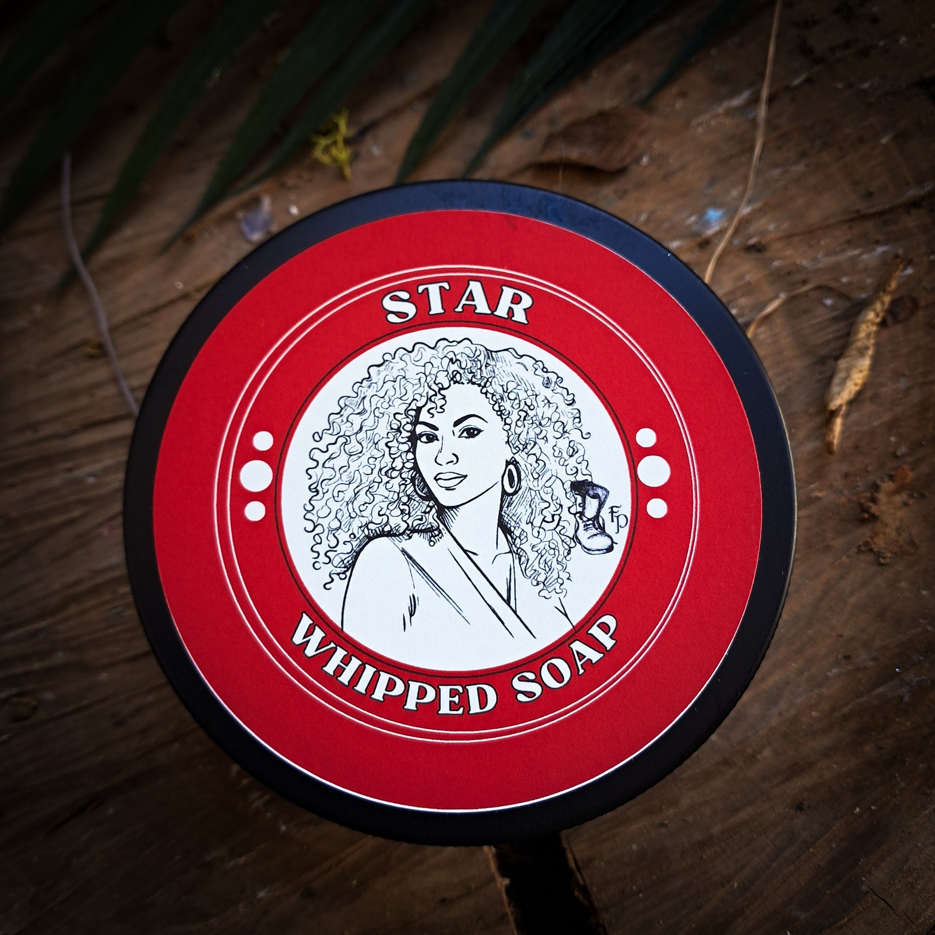 Red and black container of Star Whipped Soap on a wooden surface