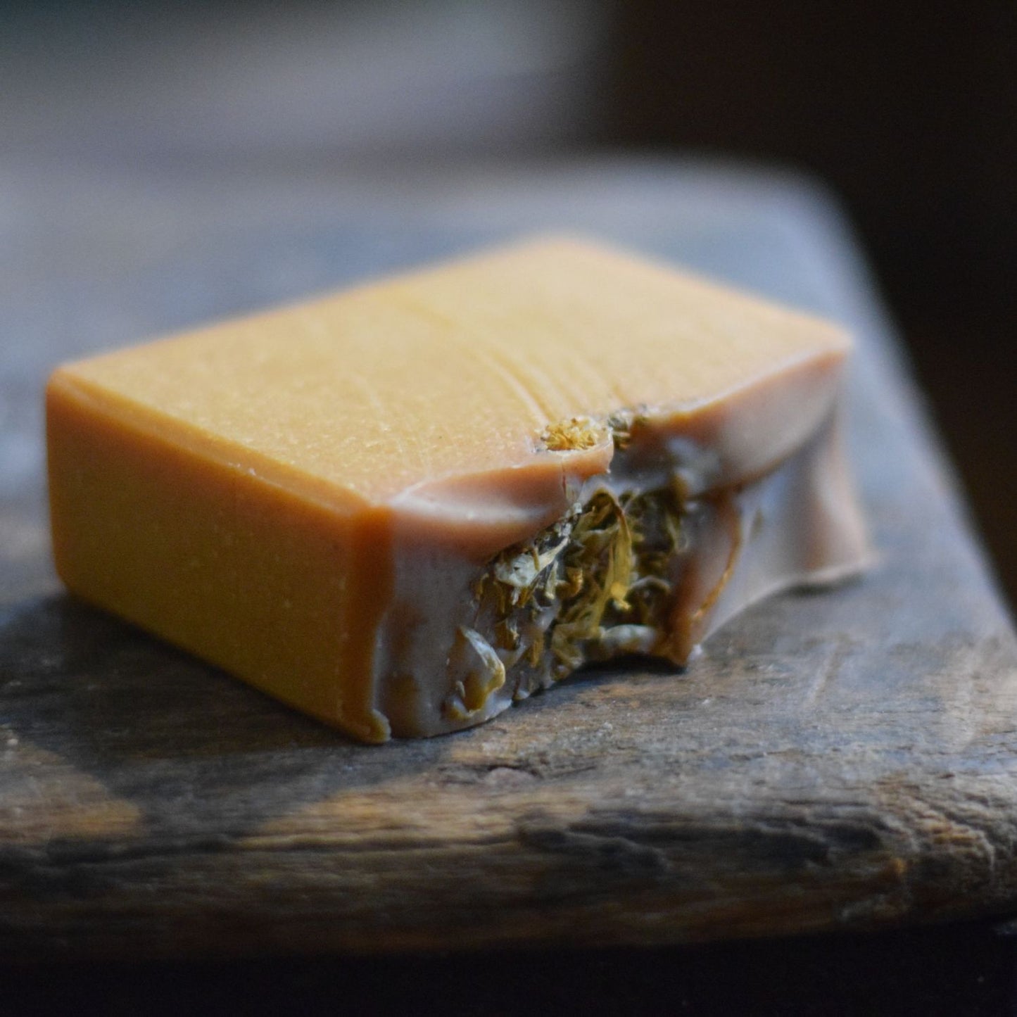 Block of orange soap with calendula  on a dark surface