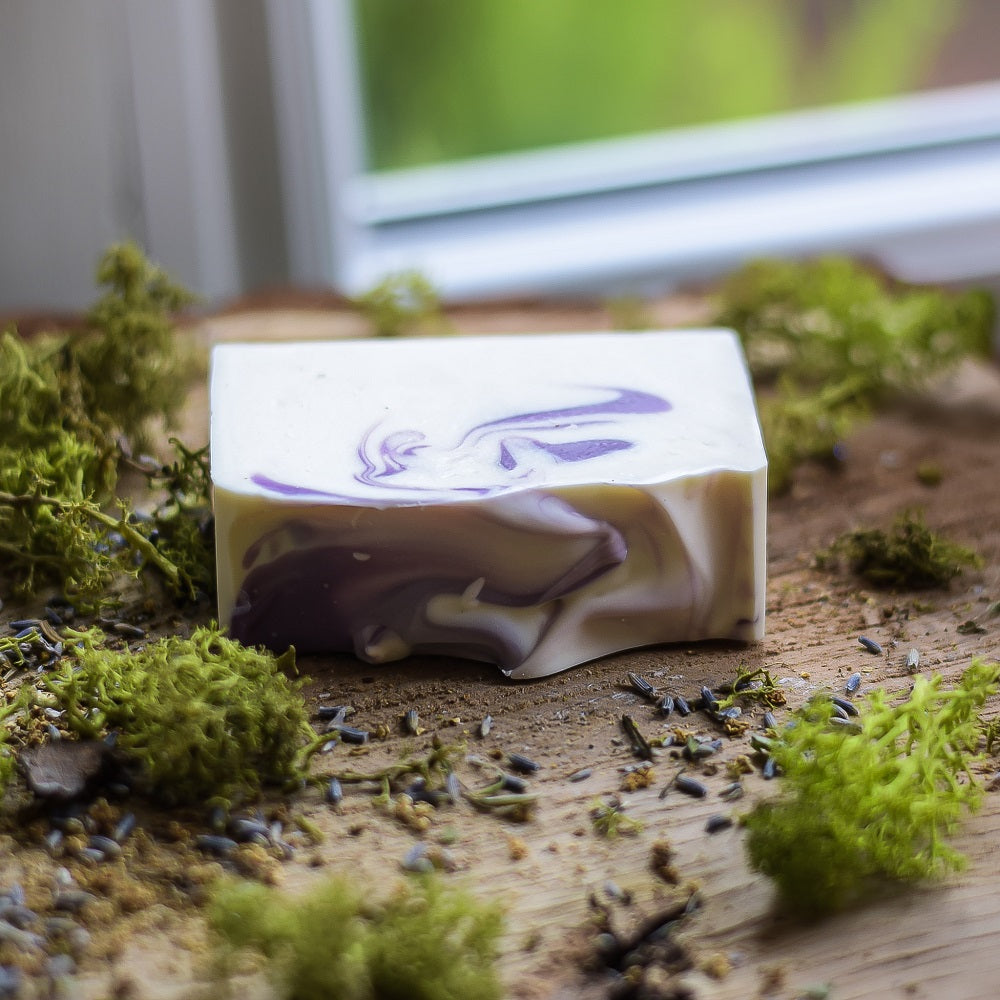 Bar of soap with a marbled design on a wooden surface with moss