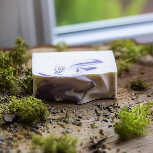 Bar of soap with a marbled design on a wooden surface with moss