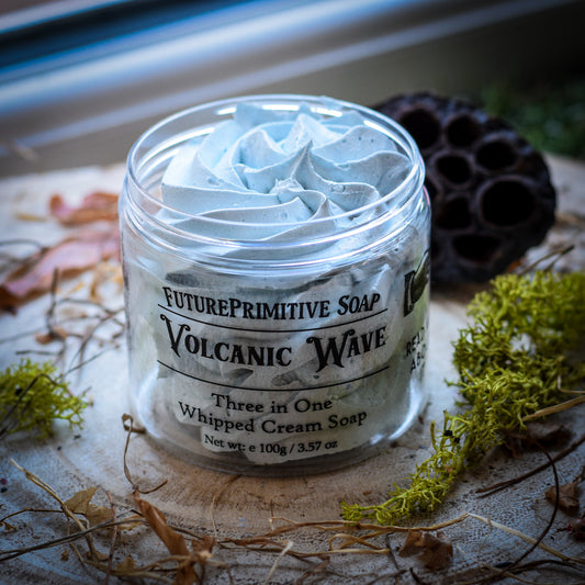 Jar of 'Volcanic Wave' whipped cream soap with a label on a rustic surface.