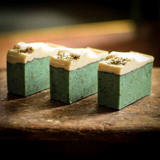 Three green soap bars with white tops on a wooden surface