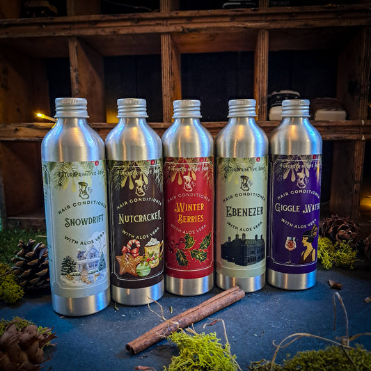 Five silver bottles with colorful labels on a rustic wooden shelf background.