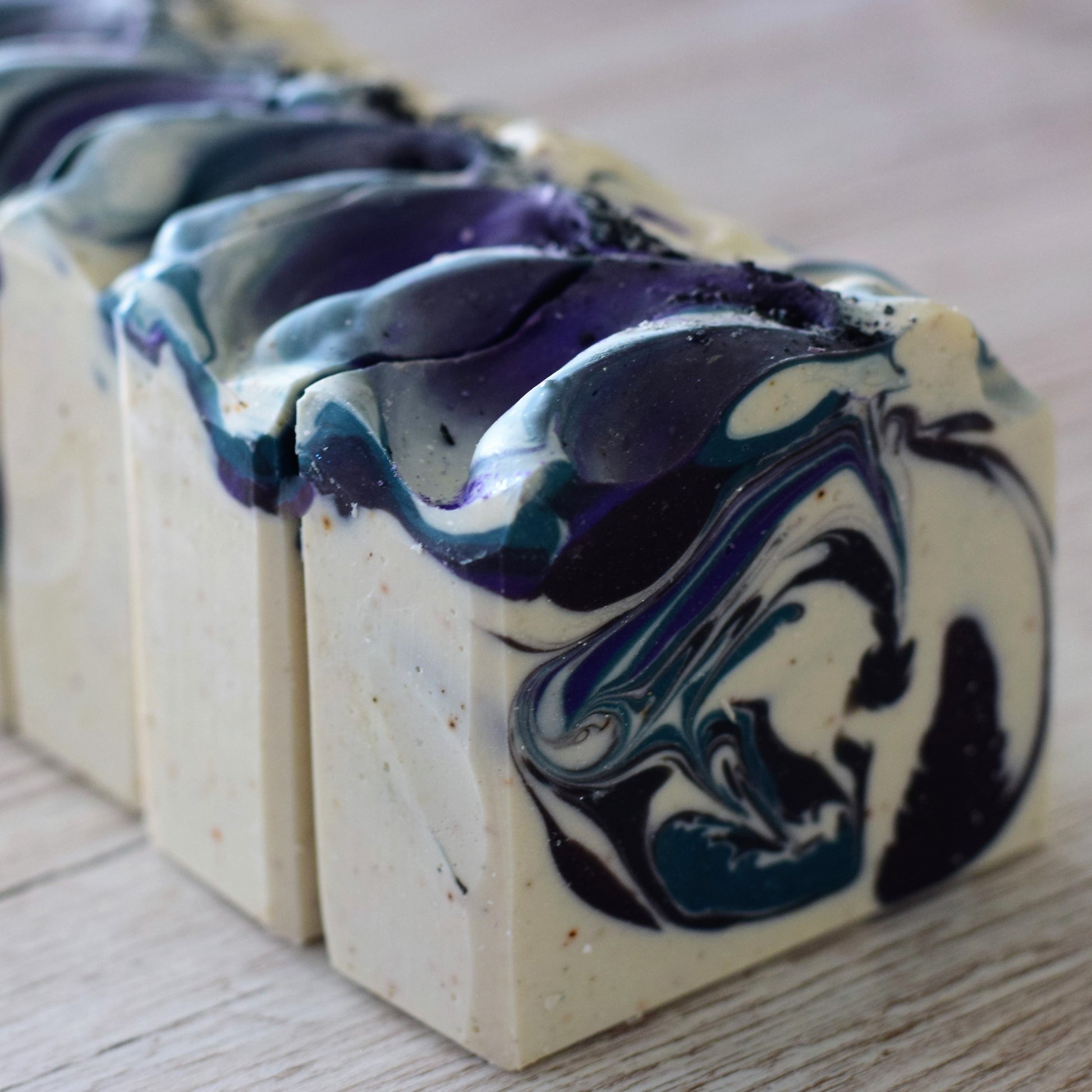 Marbled soap bars with blue and black swirls on a wooden surface