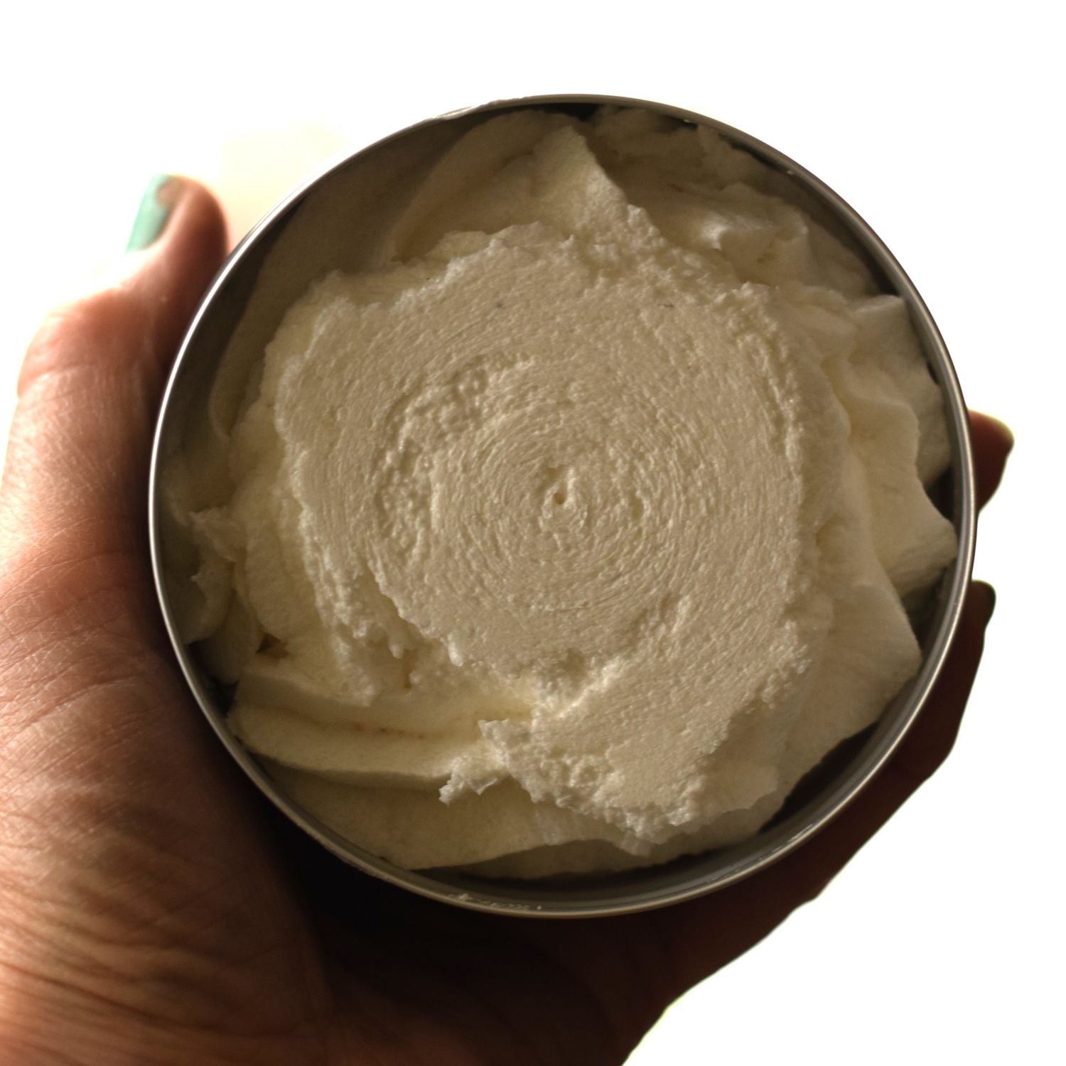 Hand holding a metal container filled with white cream