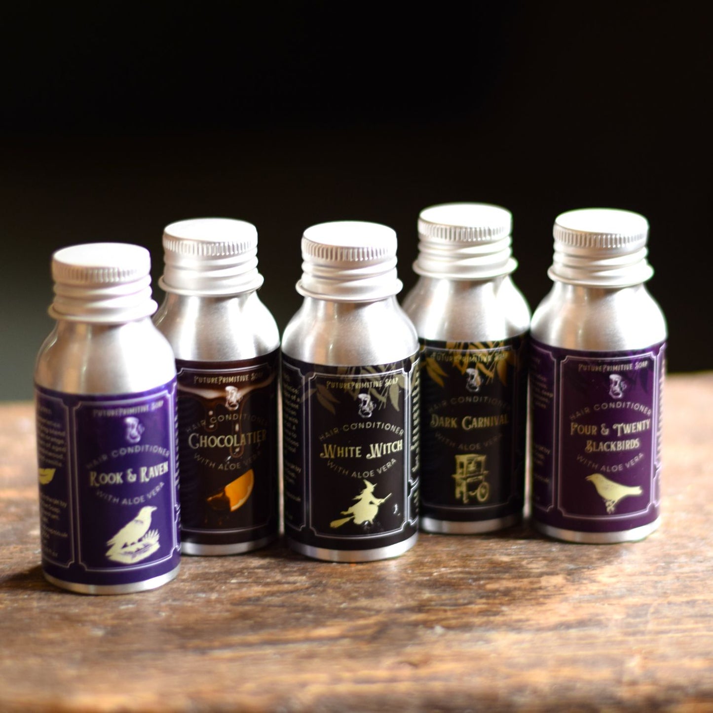 Set of six small hair conditioner bottles with labels on a wooden surface