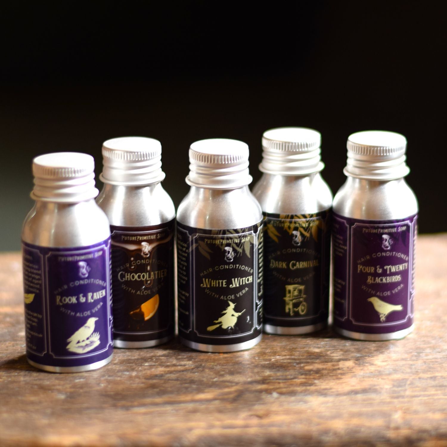 Set of six small hair conditioner bottles with labels on a wooden surface