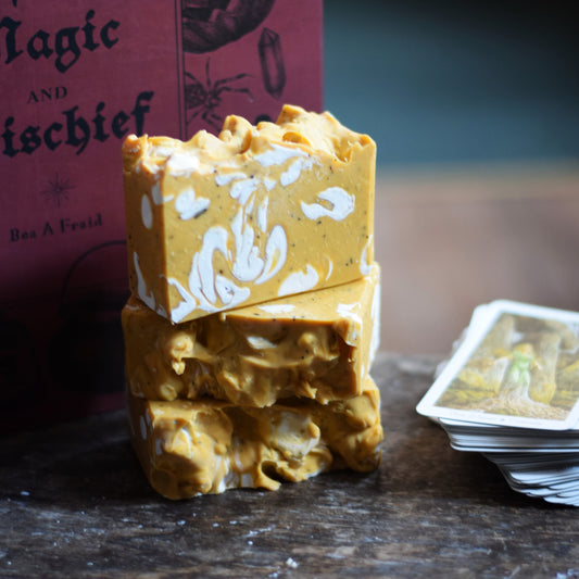 Stack of yellow and white soap bars with a pink box labeled 'Magic and Mischief' in the background.