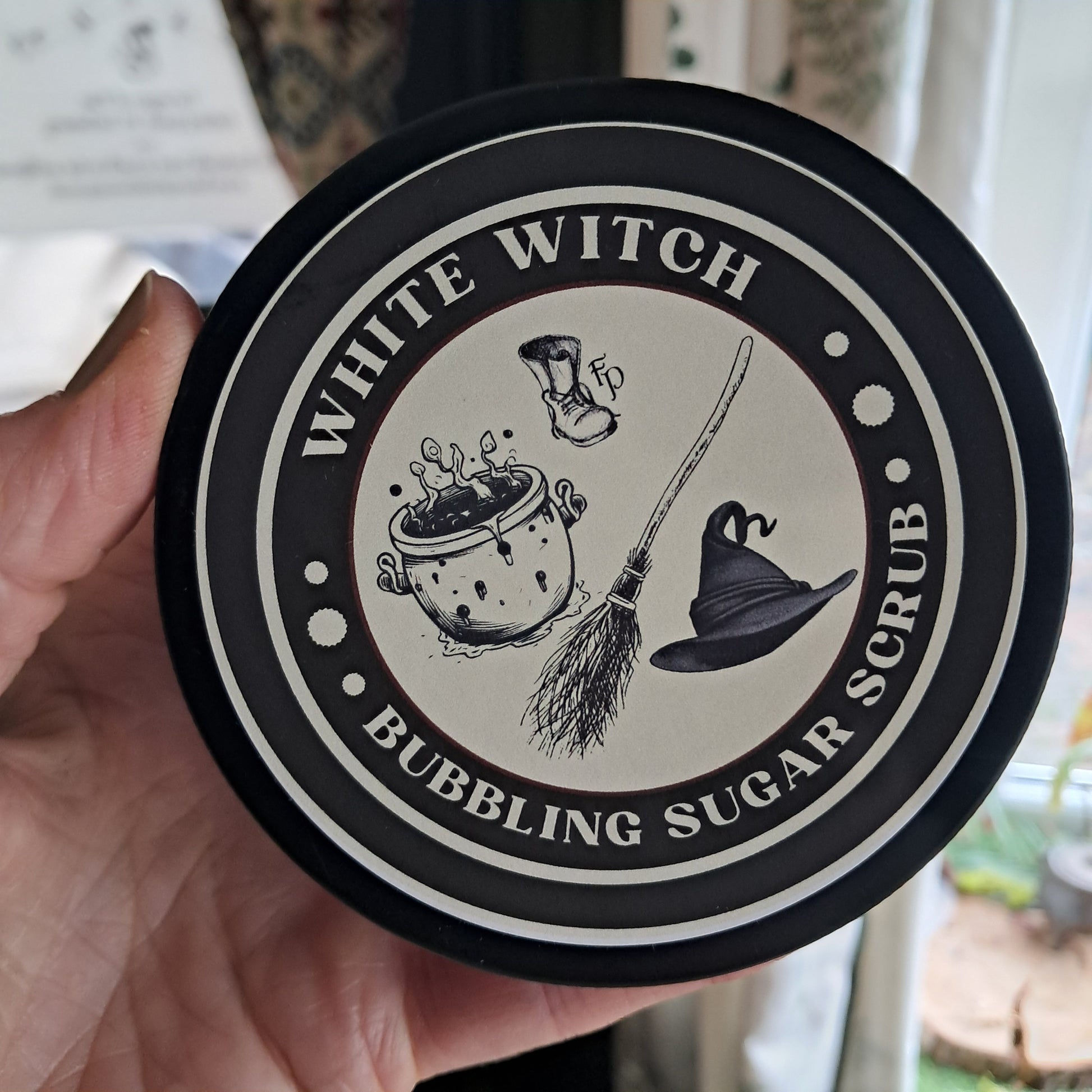 Round container lid with 'White Witch' branding and witch-themed illustrations.