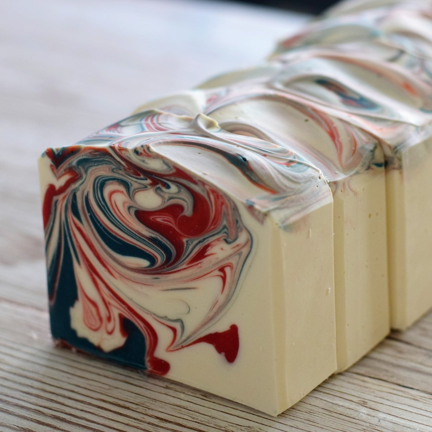 Marbled soap bars with red, white, and blue swirls on a wooden surface.
