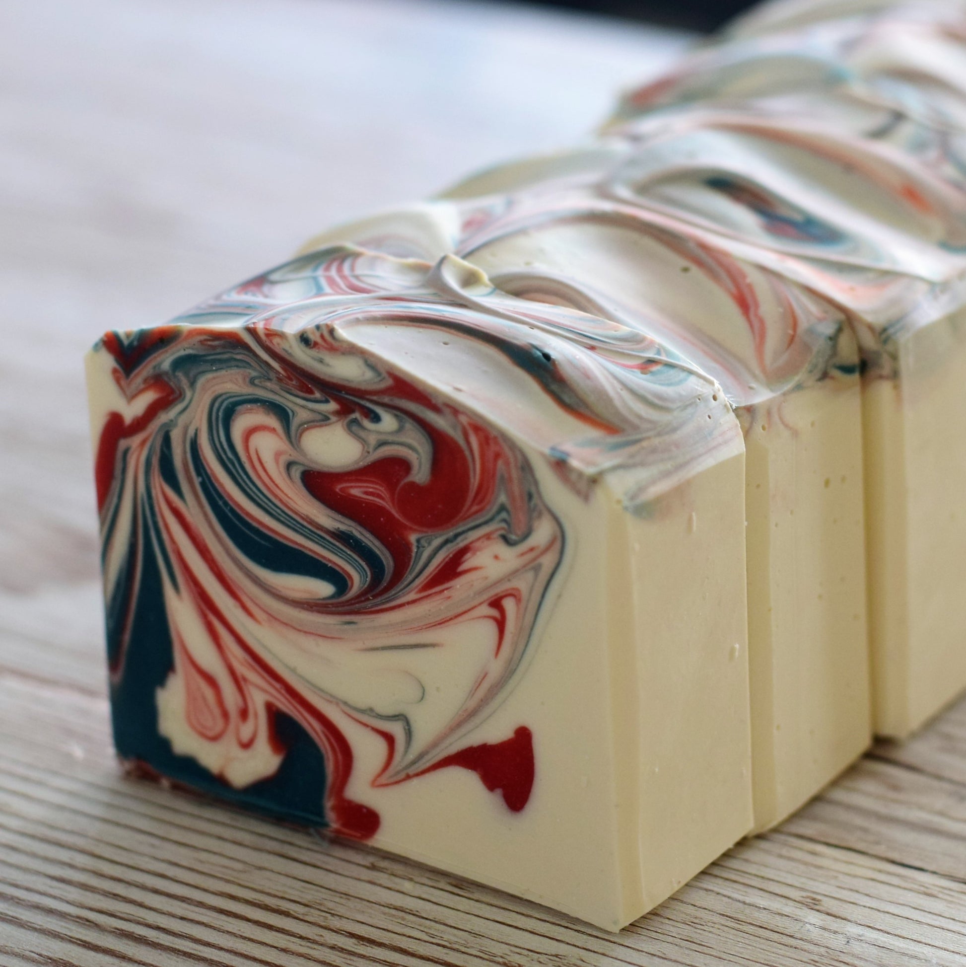 Marbled soap bars with red, white, and blue swirls on a wooden surface.
