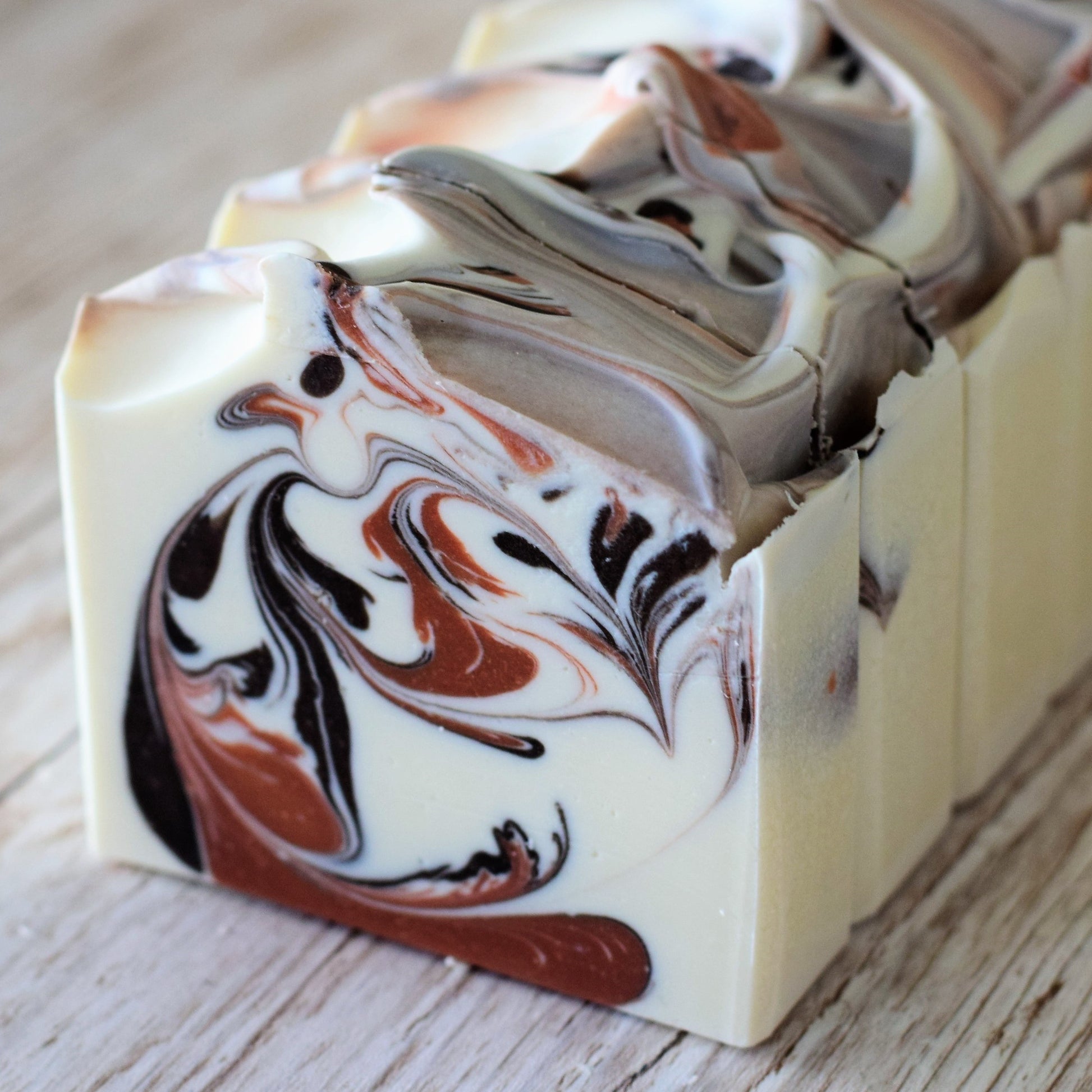 Marbled soap bar with brown and black swirls on a wooden surface
