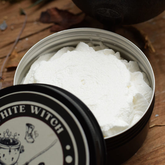 Open tin of white cream with 'White Witch' branding on a wooden surface